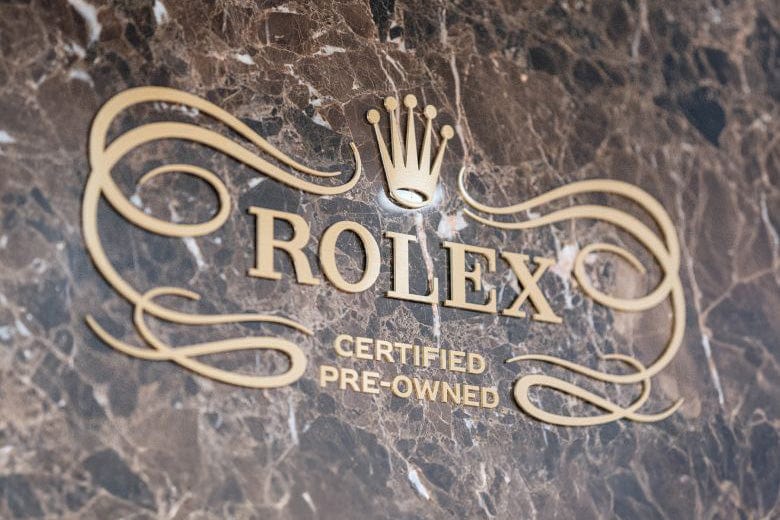 Rolex logo with Certified Pre-Owned text on a marble-patterned background.