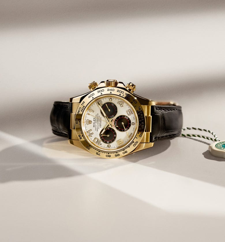 A gold wristwatch with a black leather strap and multiple dials is lying on a surface next to a green and white tag.