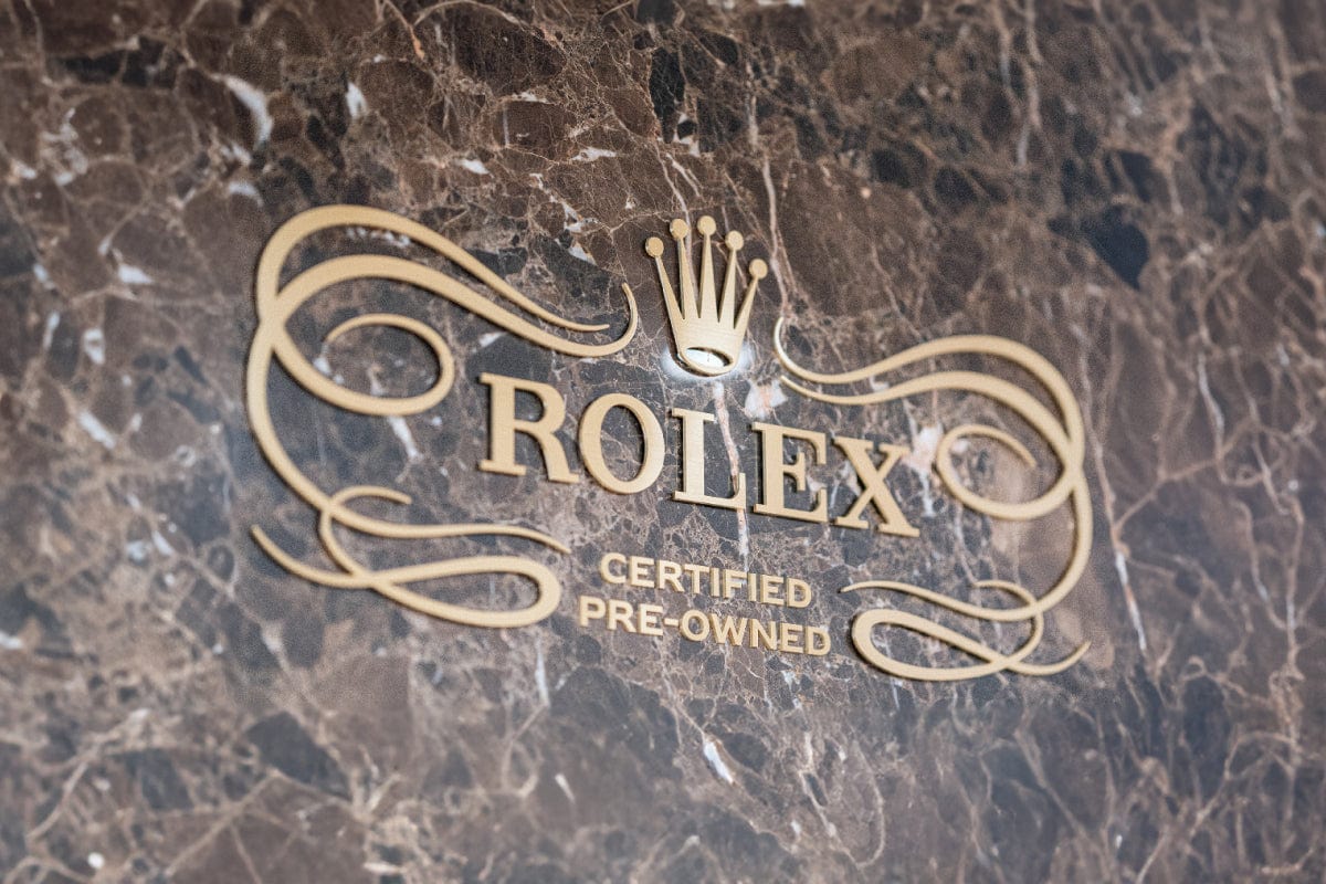 Rolex logo with Certified Pre-Owned text on a brown marble background.