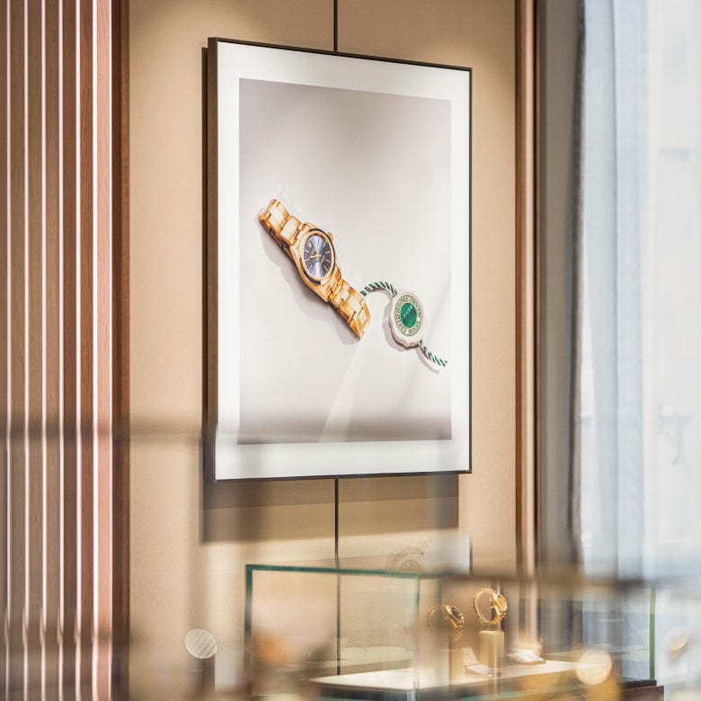 A framed image of two watches is displayed on a wall above a glass case containing various wristwatches.