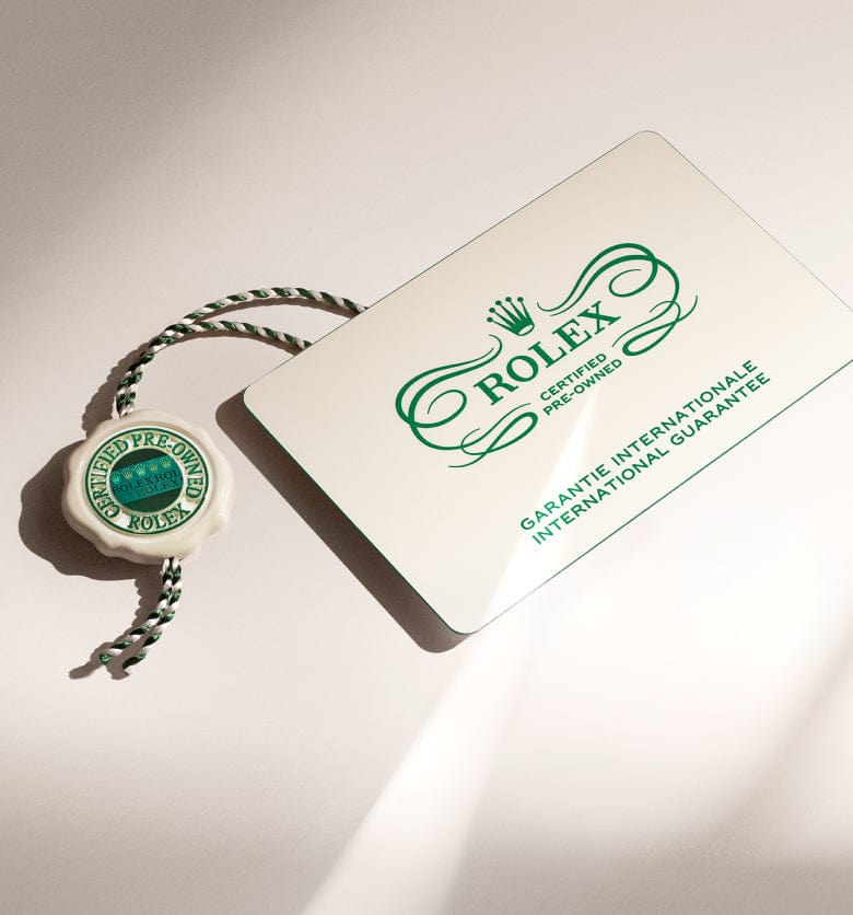 Rolex certified pre-owned guarantee card and tag with green branding on a light background.