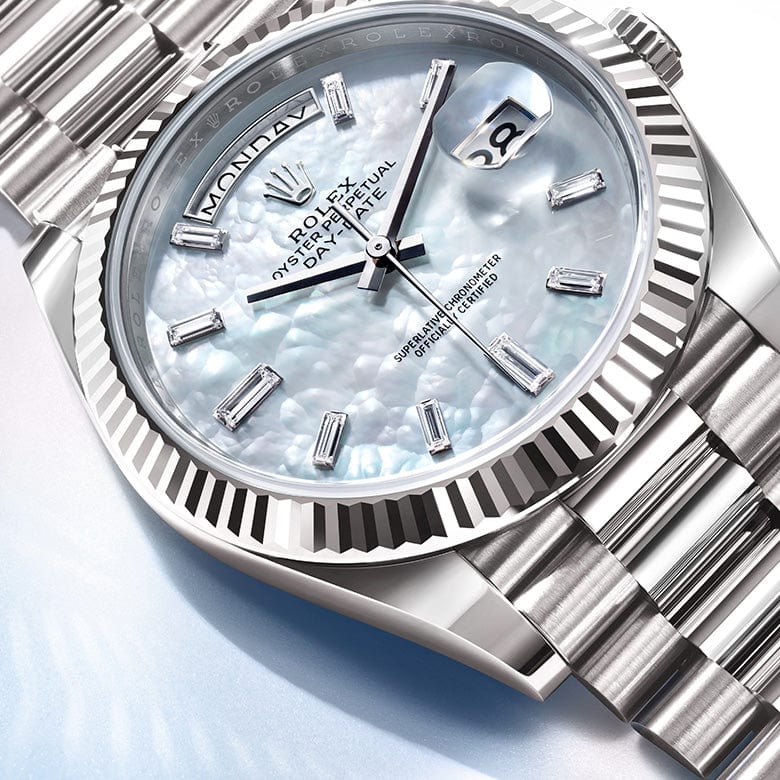 A close-up of a luxury wristwatch with a metallic band and a pearlescent dial displaying the day and date. The watch face is adorned with elegant markers, and the brand name ‚ÄúRolex‚Äù is prominently displayed below the 12 o‚Äôclock position.