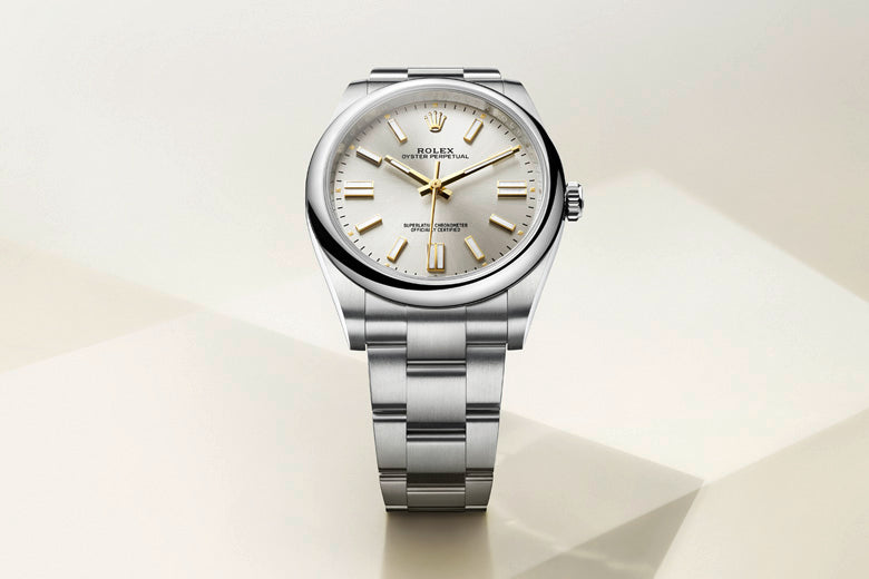 A silver wristwatch with a sleek metallic band and a light-colored dial is displayed against a gradient backdrop. The watch features gold hour markers and hands, with a sophisticated and minimalistic design.