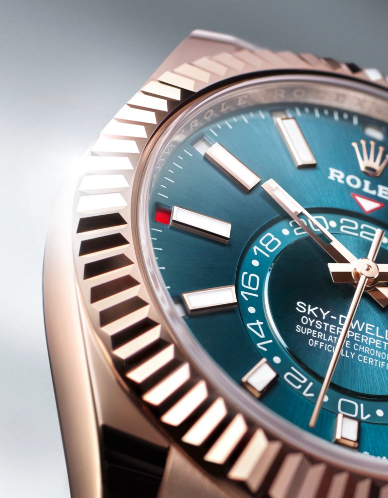 Close-up image of a luxury wristwatch with a blue dial and rose gold bezel. The watch, featuring the brand name 